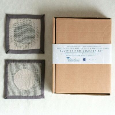 2 hand stitched coasters at the side of a packaging box