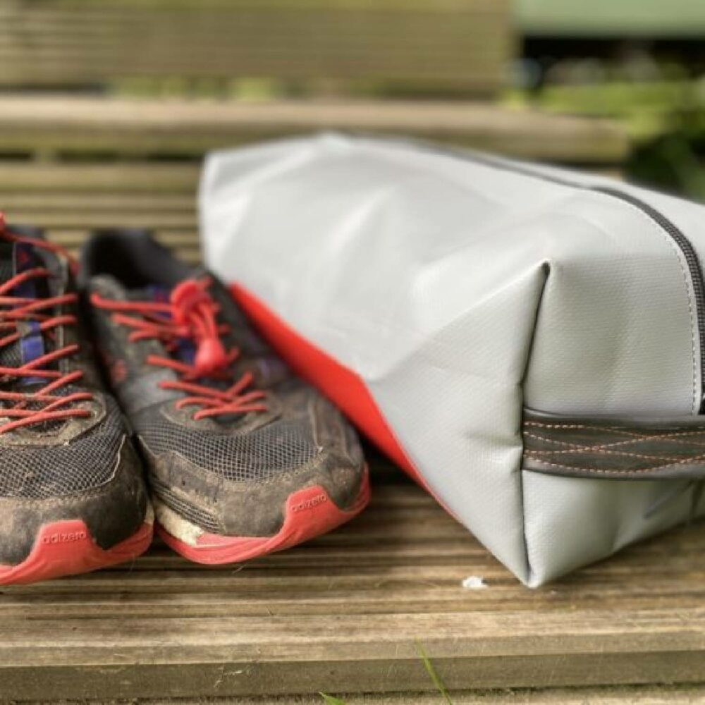 Cycle of Good Cube bag shown next to pair of dirty trainers