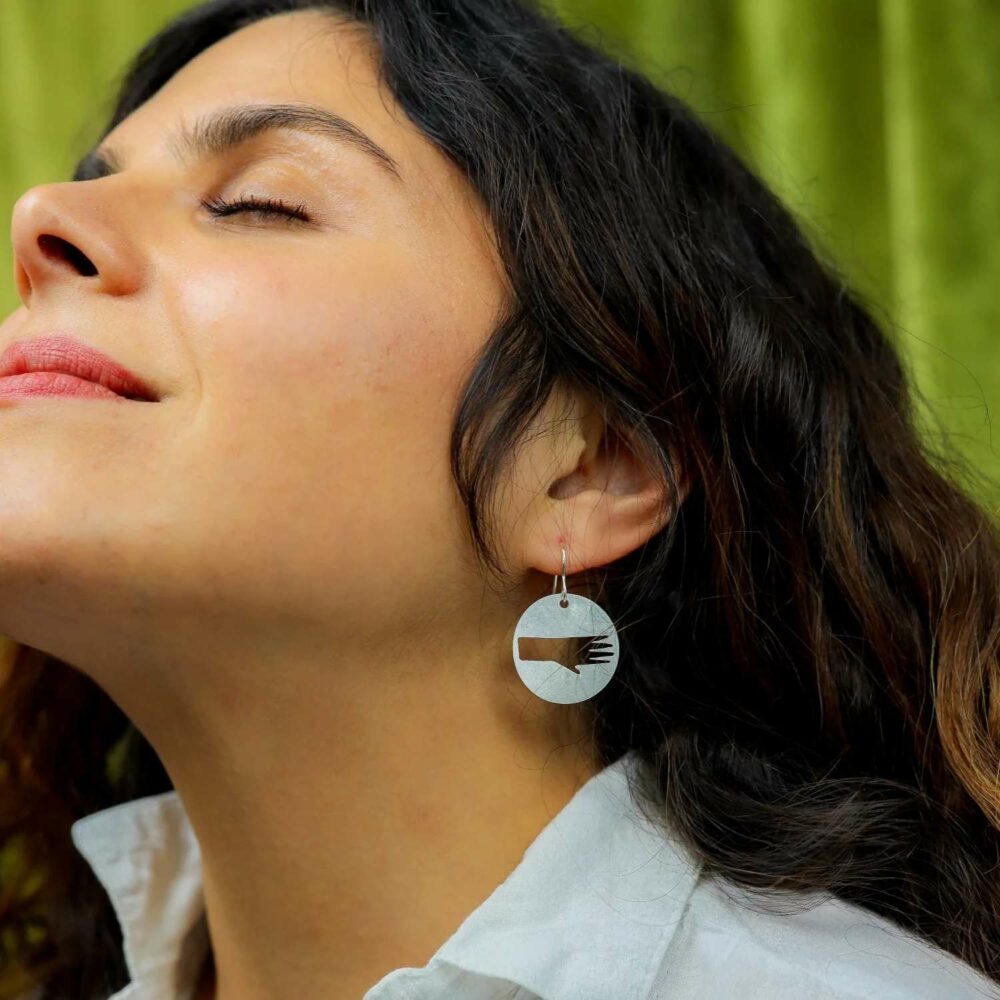 Woman wearing pivot silver hand disc earrings
