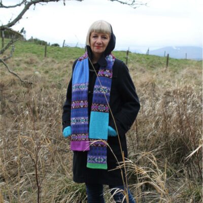 Woman standing outdoors in countryside wearing the Green Grove Weavers May Scarf